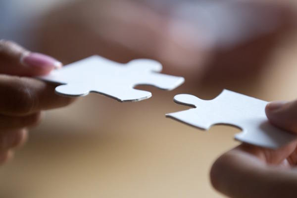 close up multiracial business team members connecting puzzle pieces