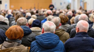 large group of residents attending town meeting. community members seated and listening to speaker in public hall. civic engagement and local discussion concept